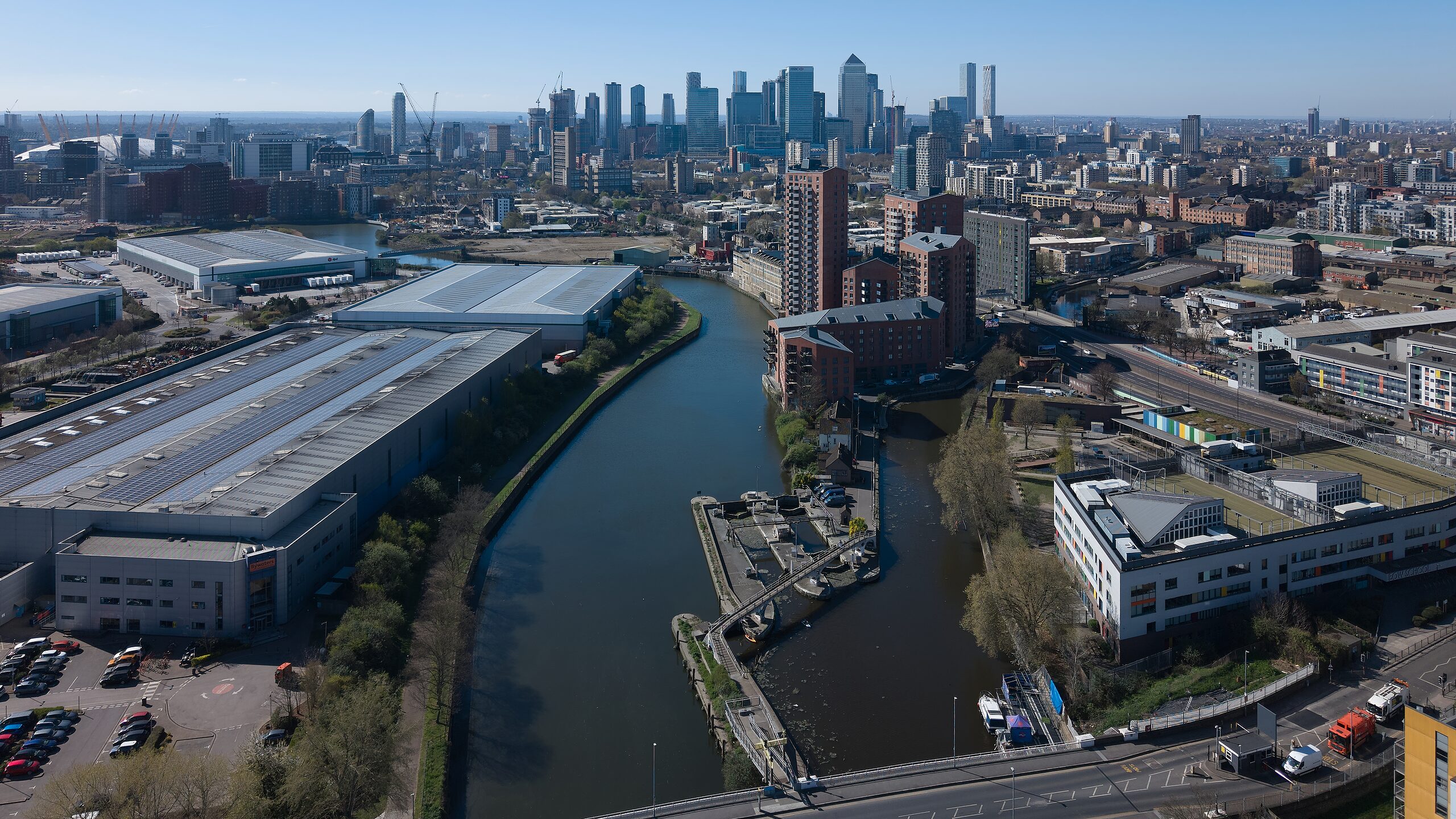 Aerial view along an east London waterway with the Canary Wharf towers on the horizon
