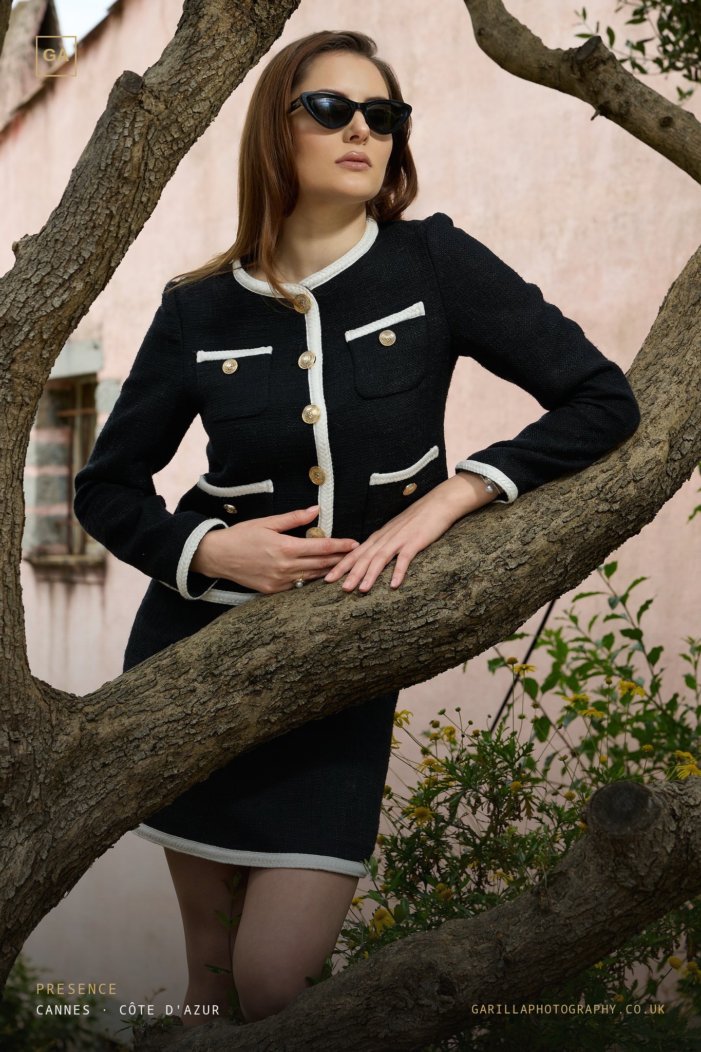 Model in black-and-cream tweed beside an olive tree — titled Presence