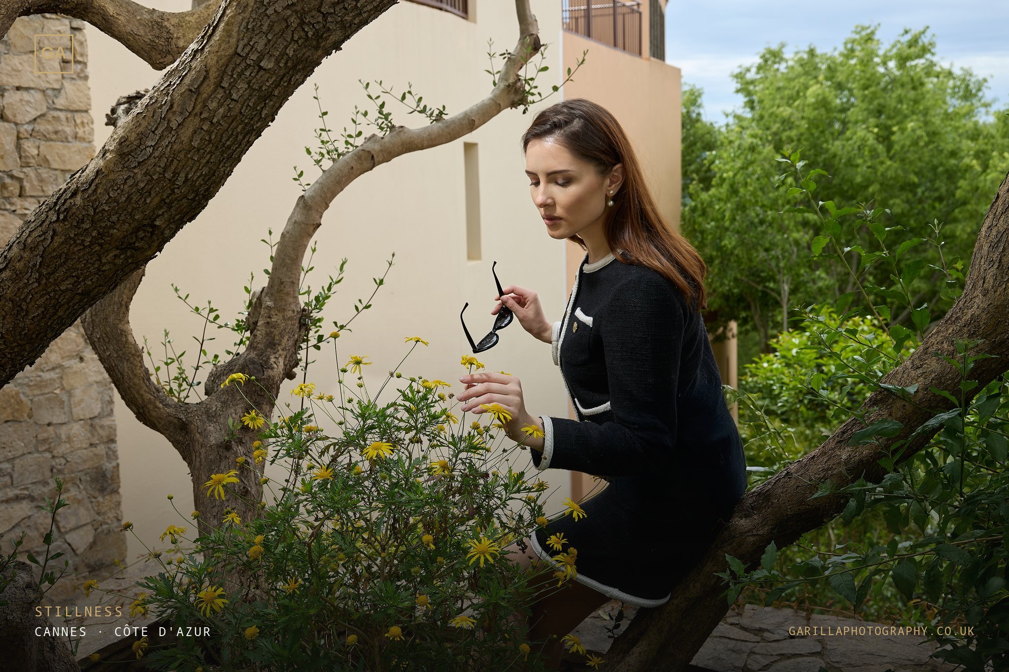 Model in black tweed touching wild yellow flowers — titled Stillness