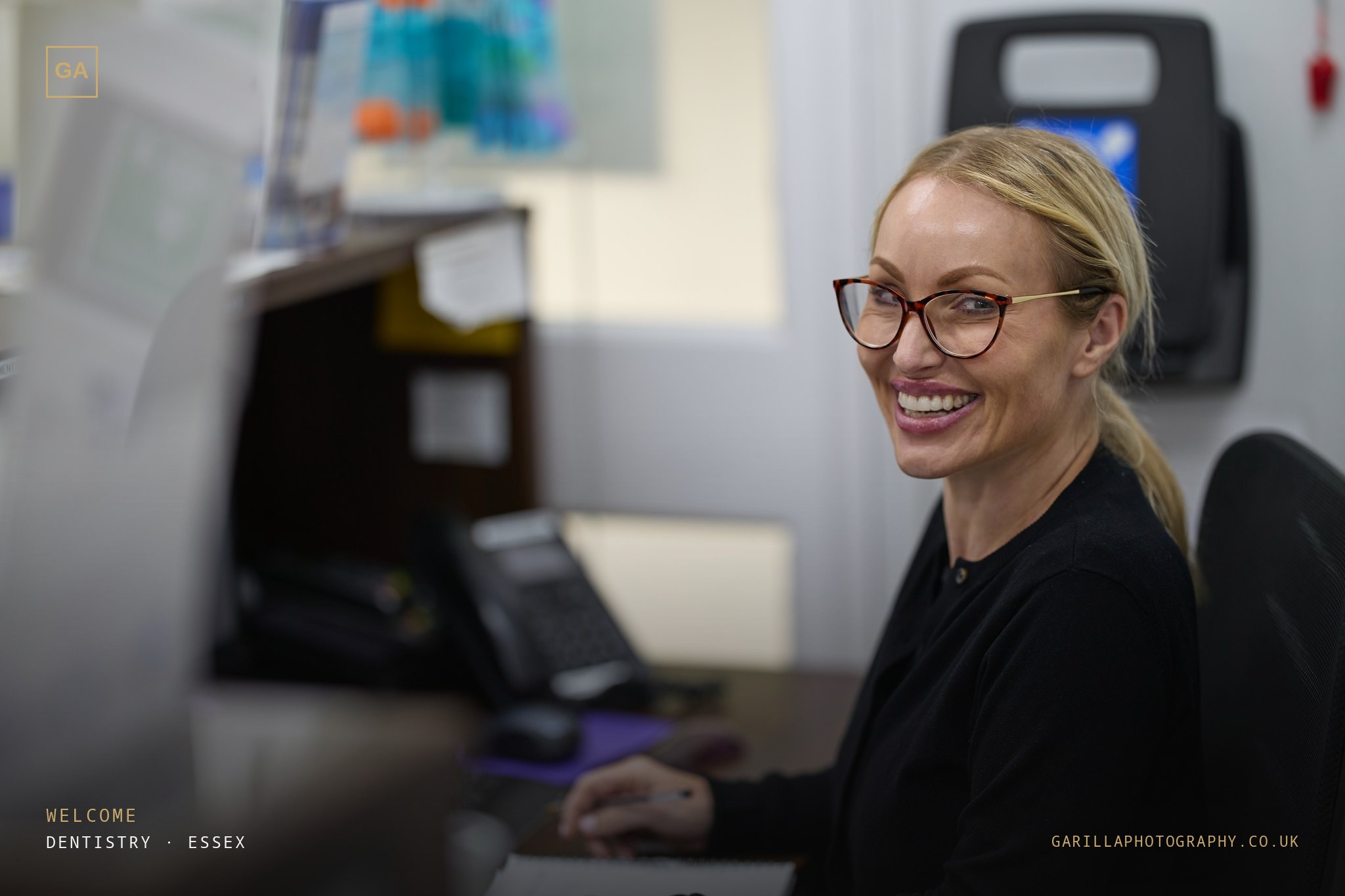 A smiling receptionist at the front desk of the practice — titled Welcome