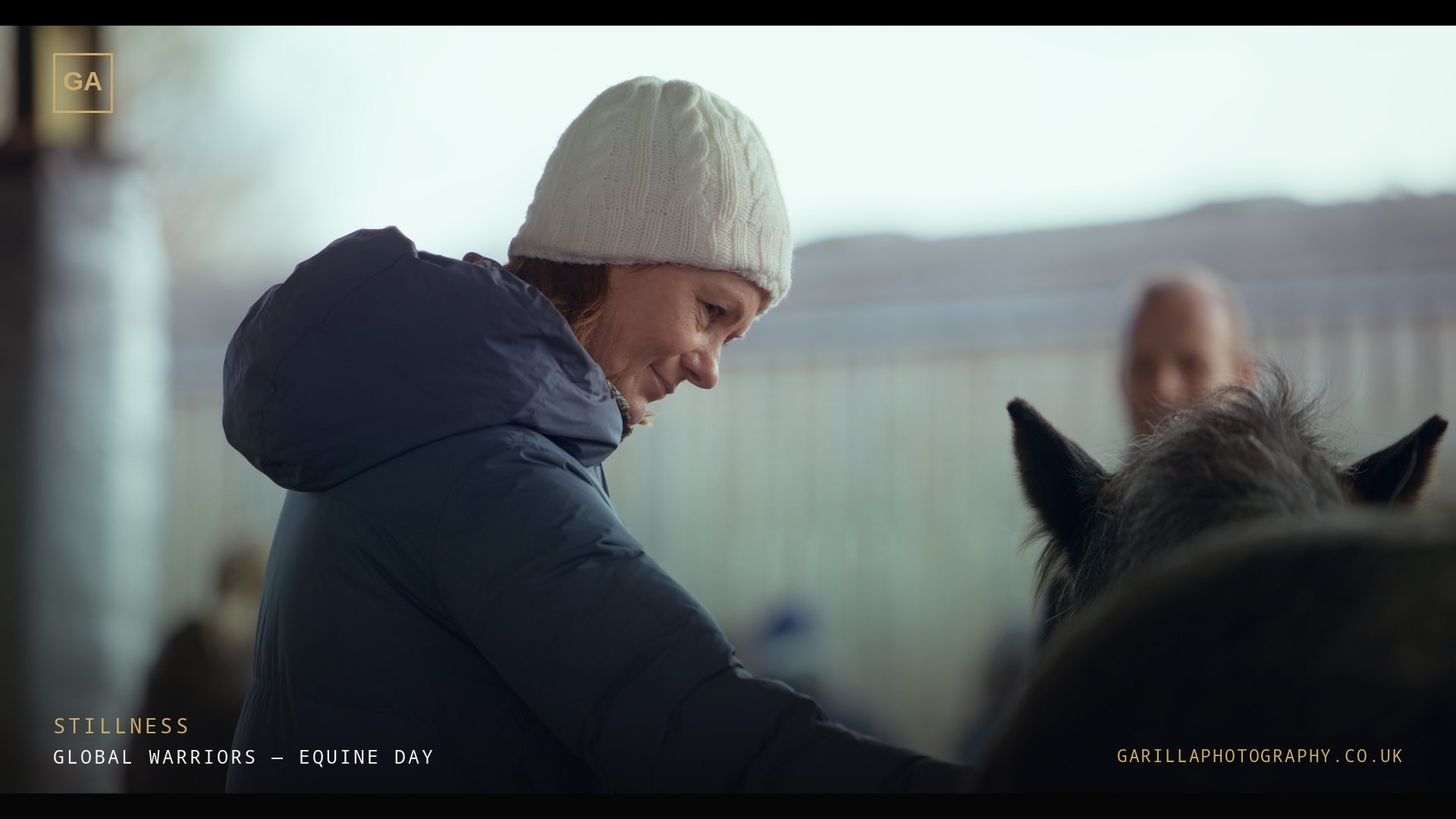 A woman in a white hat beside a horse — a still from the film, titled Stillness