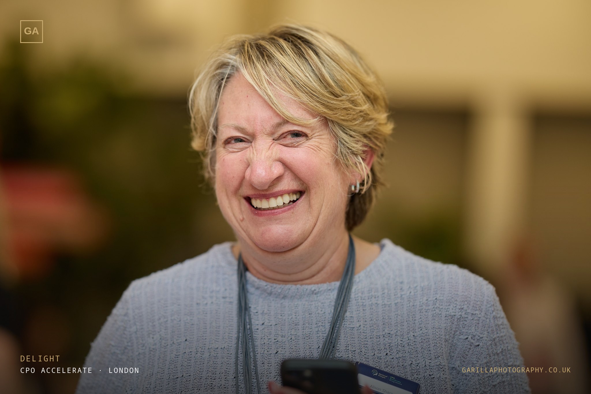 A delegate laughing, lanyard on — titled Delight