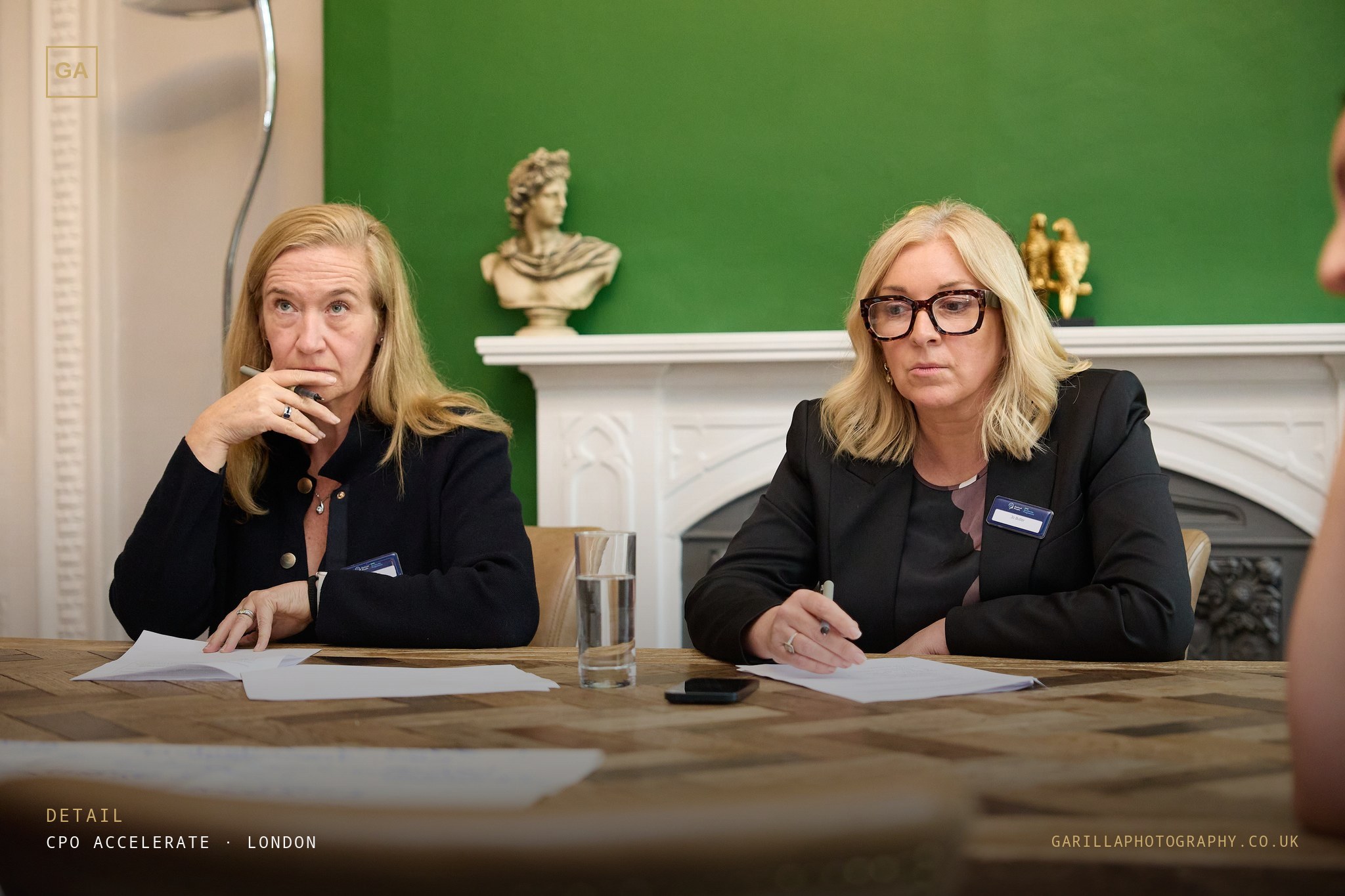 Two delegates taking notes at the table — titled Detail