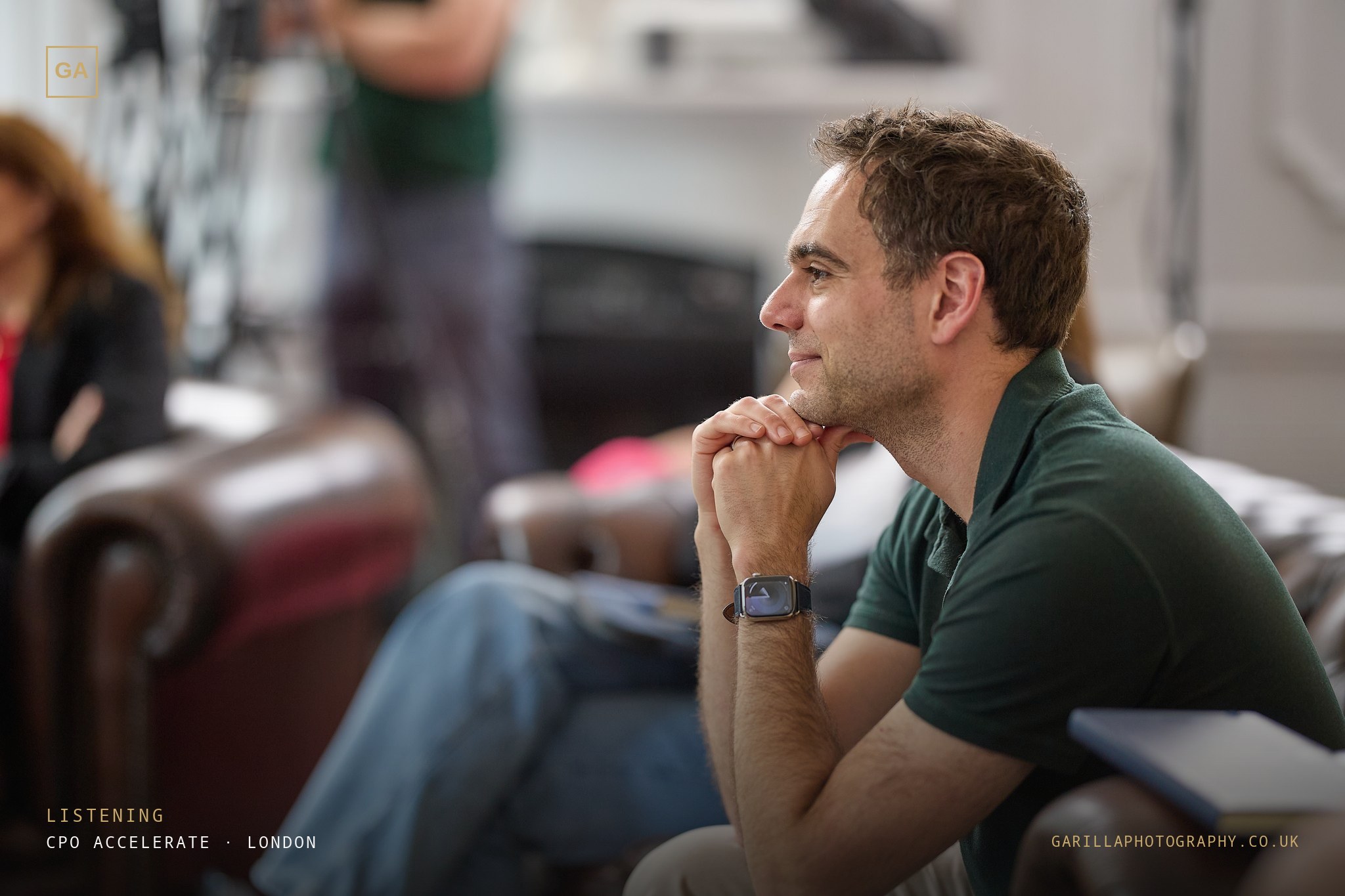 A delegate listening intently, hands clasped — titled Listening