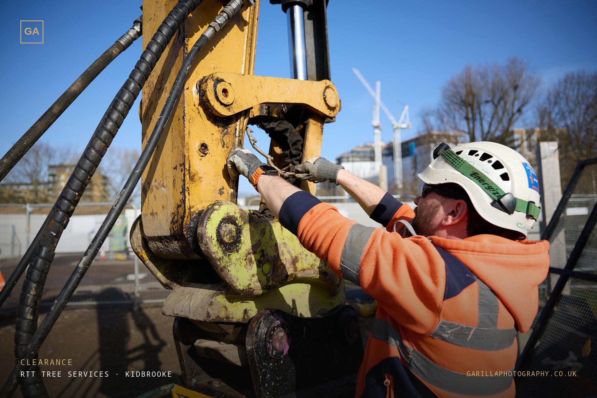 A groundworker rigging the grapple attachment on the excavator arm — titled Clearance