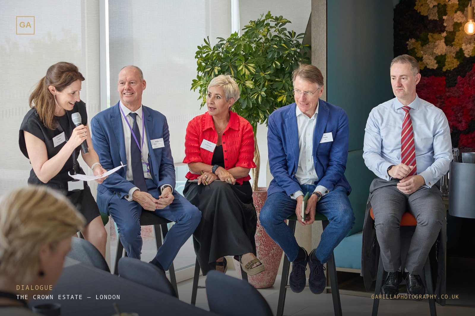 The panel mid-discussion, host smiling with microphone