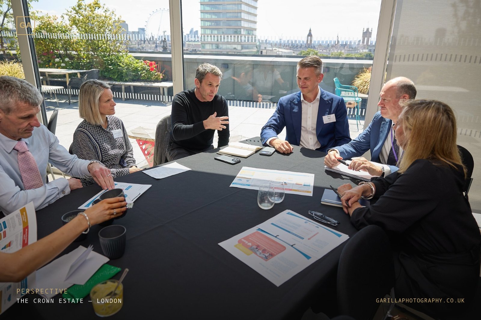 A roundtable in discussion with the London skyline beyond the terrace